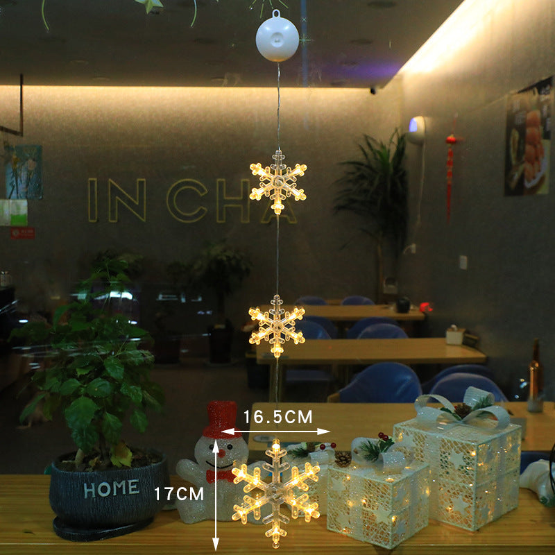 Three warm-white LED star pendants hanging in a window