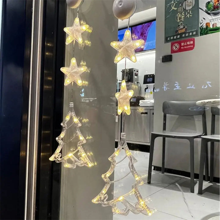 Three warm-white LED star pendants hanging in a window