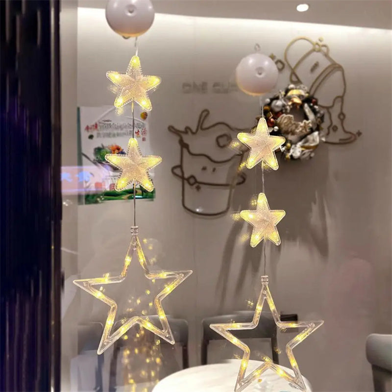 Three warm-white LED star pendants hanging in a window