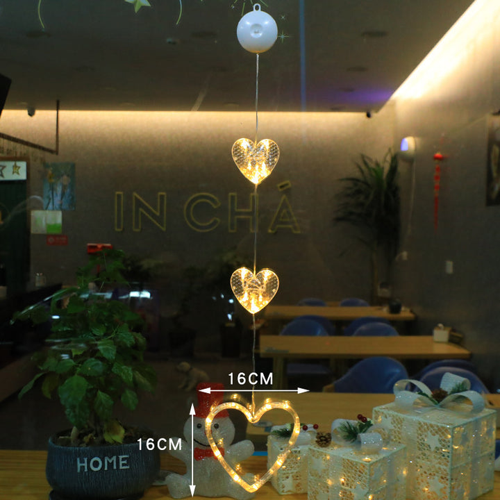Three warm-white LED star pendants hanging in a window