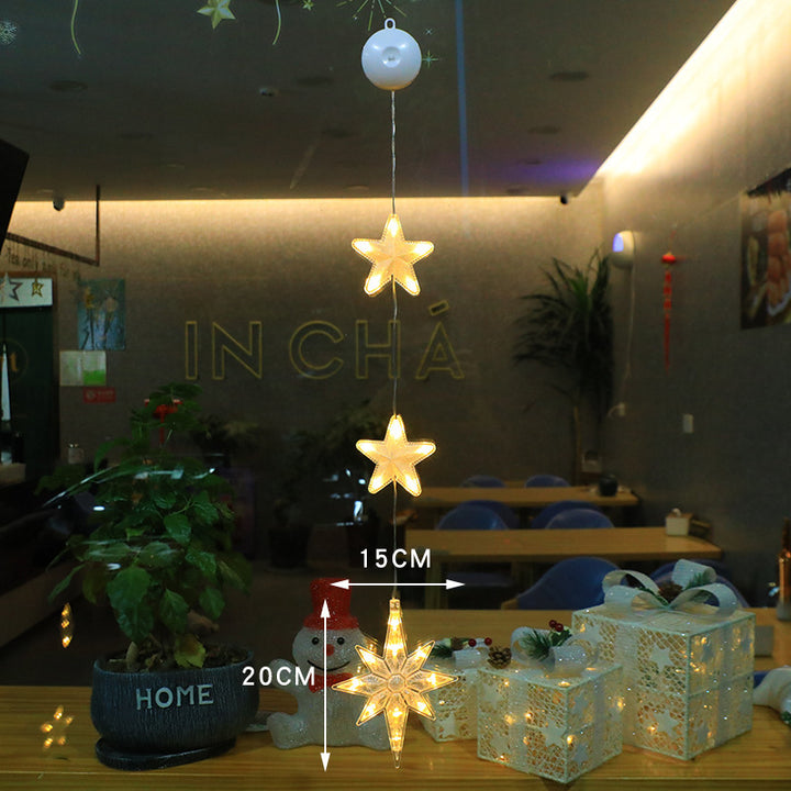 Three warm-white LED star pendants hanging in a window