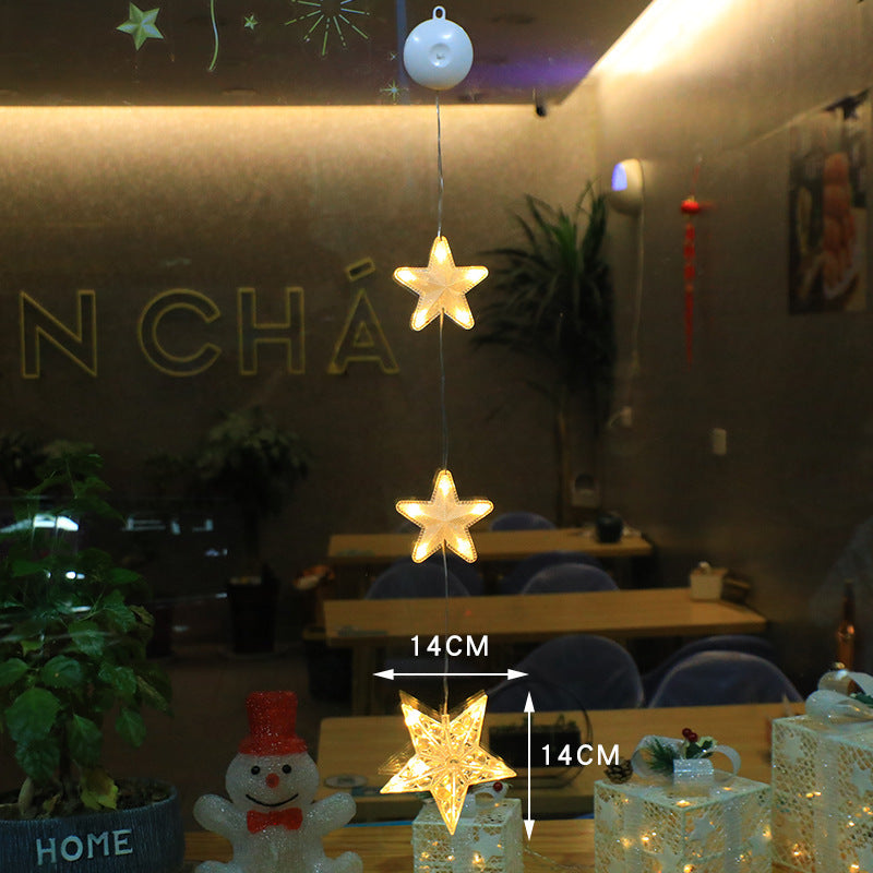 Three warm-white LED star pendants hanging in a window