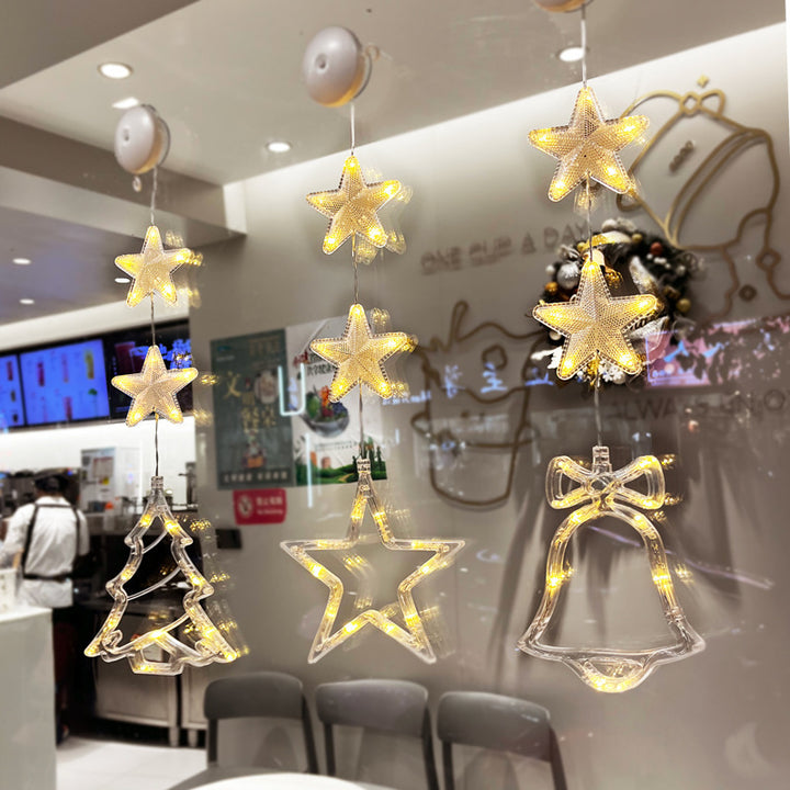 Three warm-white LED star pendants hanging in a window