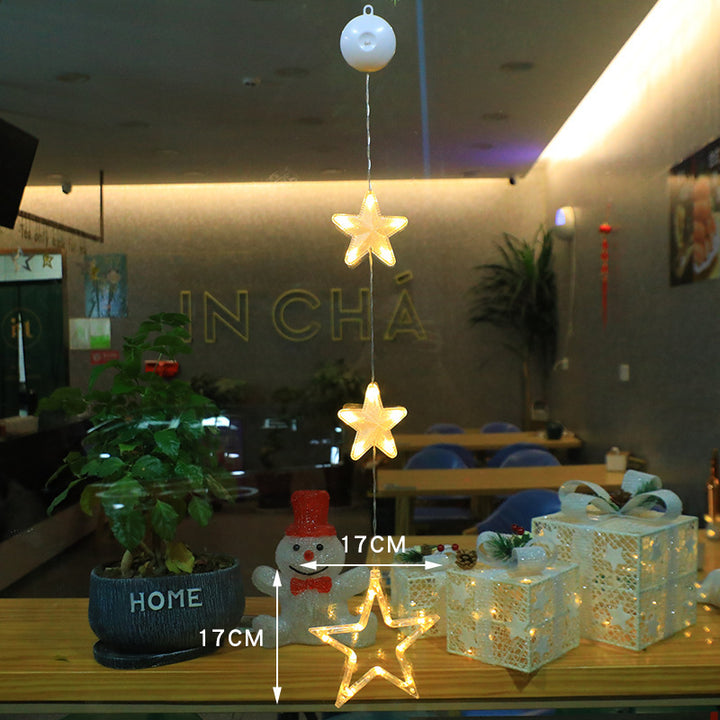 Three warm-white LED star pendants hanging in a window