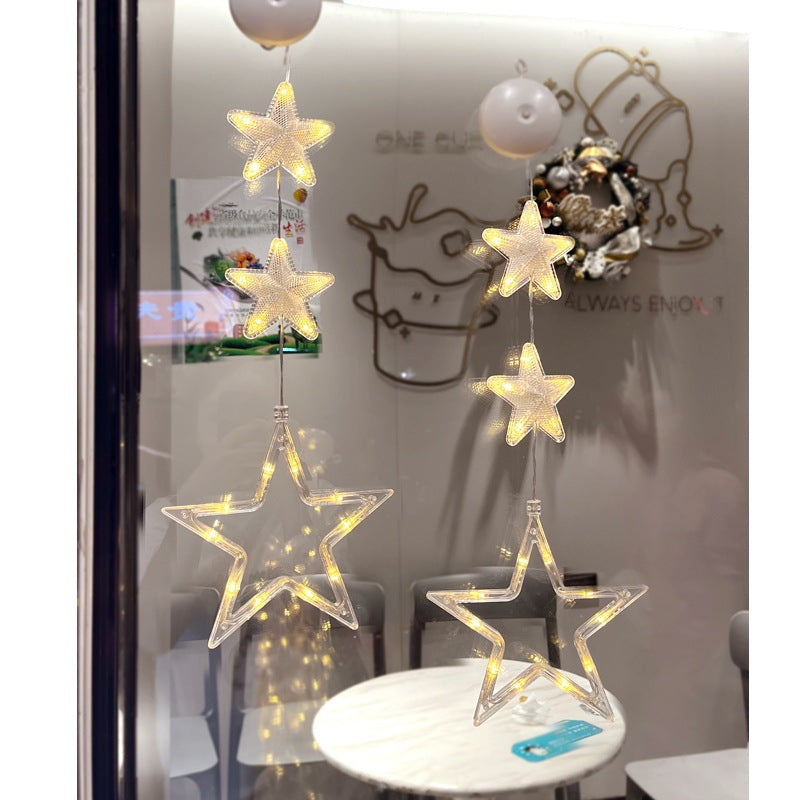 Three warm-white LED star pendants hanging in a window